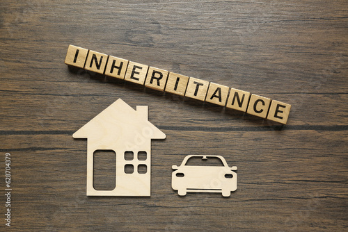 Foto Word Inheritance made with cubes, cutouts of car and house on wooden table, flat