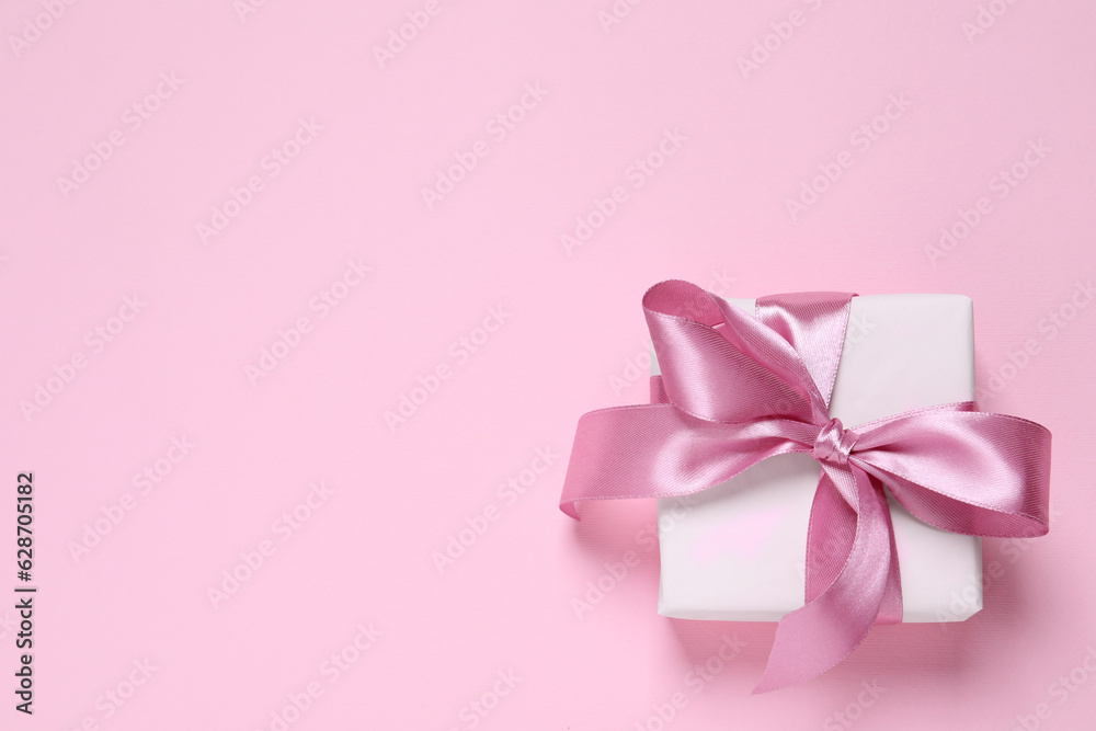Beautiful gift box with bow on pink background, top view. Space for text Beautiful gift box with bow on pink background, top view. Space for text