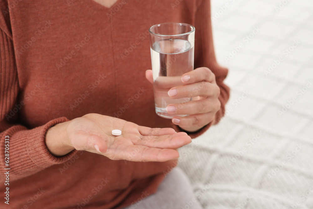 Senior woman with pill and glass of water indoors, closeup Senior woman with pill and glass of water indoors, closeup