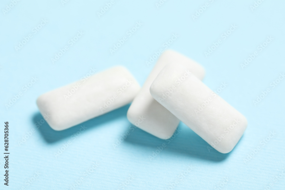 Tasty white chewing gums on light blue background, closeup Tasty white chewing gums on light blue background, closeup