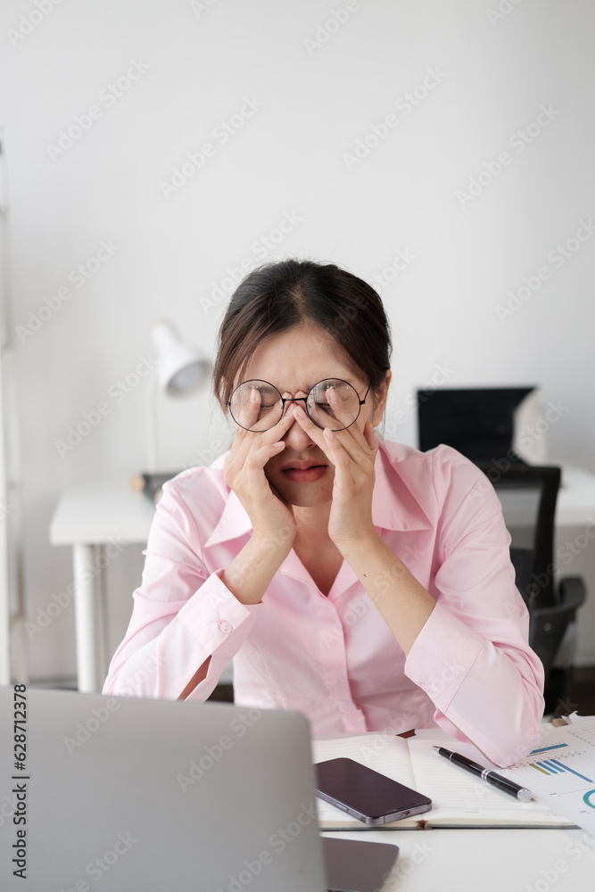 Tired and exhausted young Asian businesswoman feeling upset and lost focus after working for a loong hours. Tired and exhausted young Asian businesswoman feeling upset and lost focus after working for a loong hours.