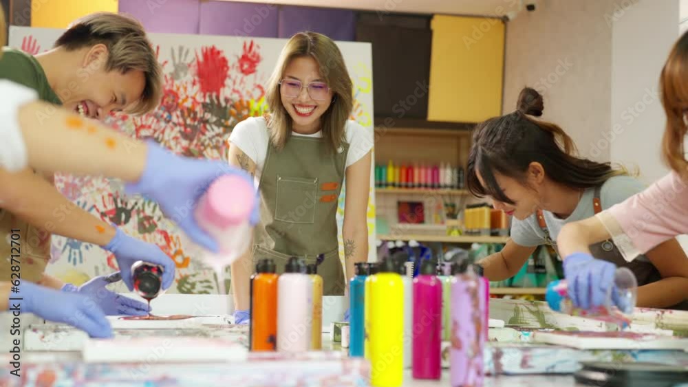 Group of Asian generation z people learning acrylic pouring art on canvas workshop at art studio. Young artist university student enjoy and fun creating colorful abstract modern art painting in class. Group of Asian generation z people learning acrylic pouring art on canvas workshop at art studio. Young artist university student enjoy and fun creating colorful abstract modern art painting in class.