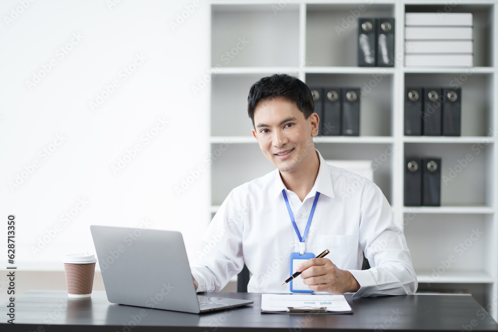 Portrait of young handsome Asian businessman working with laptop computer in the office room.