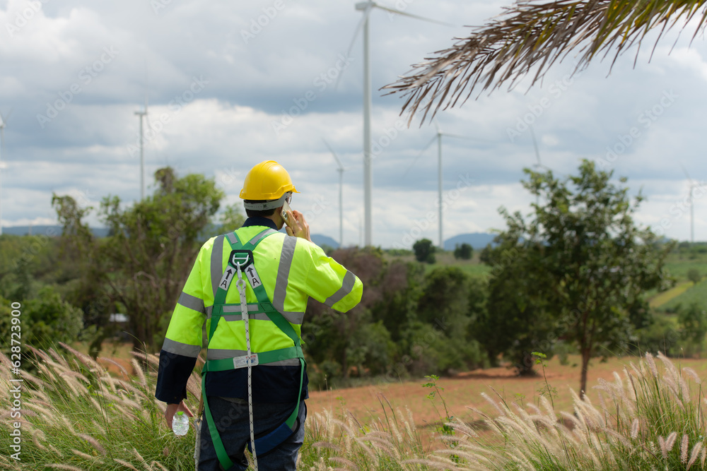 Engineers are using a smartphone to check the wind turbine in the field, The concept of natural energy from wind. Engineers are using a smartphone to check the wind turbine in the field, The concept of natural energy from wind.