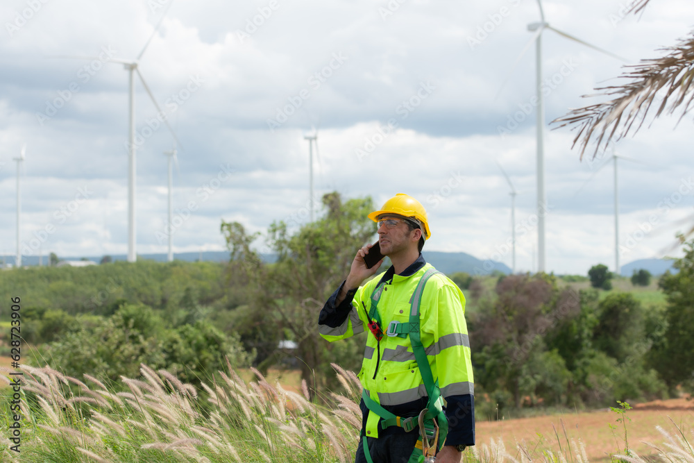 Engineers are using a smartphone to check the wind turbine in the field, The concept of natural energy from wind. Engineers are using a smartphone to check the wind turbine in the field, The concept of natural energy from wind.