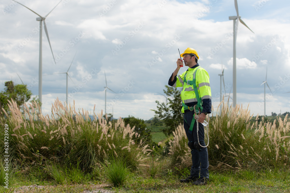 Engineers are using a smartphone to check the wind turbine in the field, The concept of natural energy from wind.