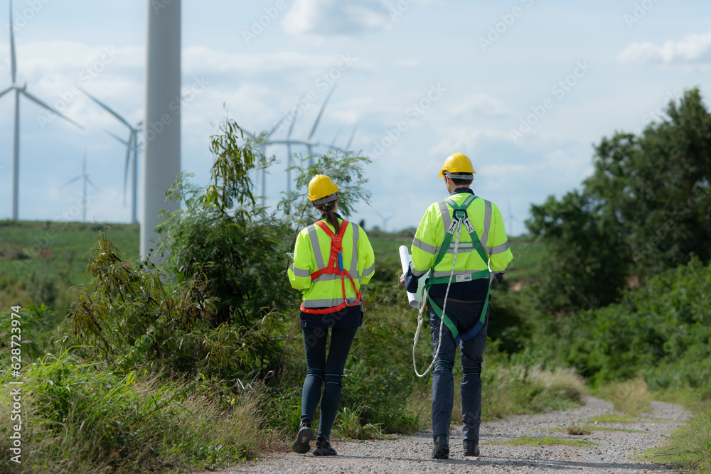 Engineers and wind turbines in a wind farm in the countryside with daily audit tasks mission