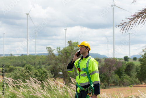 Engineers are using a smartphone to check the wind turbine in the field, The concept of natural energy from wind.