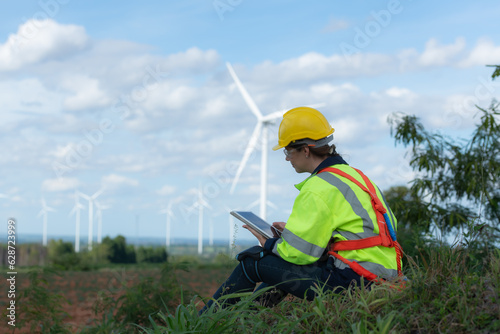 Engineers are using a tablet to check the wind turbine in the field, The concept of natural energy from wind.