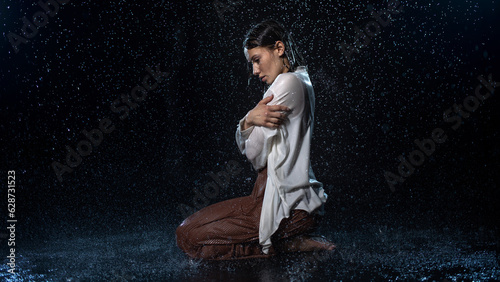 Bild auf Leinwand young woman in the rain, getting wet through, wet clothes and water running down her face