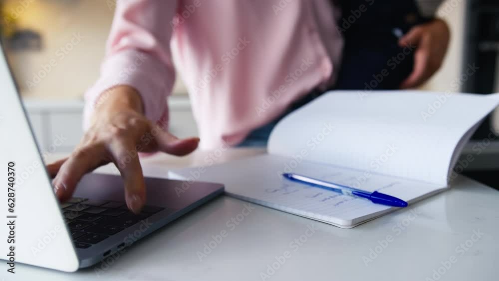 Close up of busy working mother looking after young son whilst using laptop and boy plays with her mobile phone - shot in slow motion Close up of busy working mother looking after young son whilst using laptop and boy plays with her mobile phone - shot in slow motion