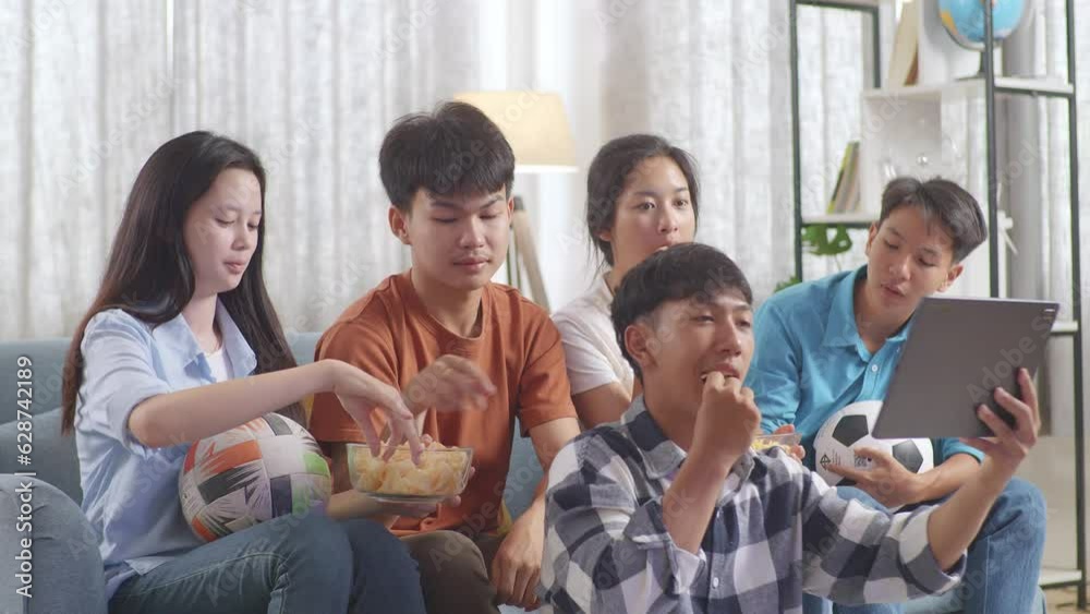 Asian Teenagers Cheering, Eating And Watching Football Game On Tablet At Home
Asian Teenagers Cheering, Eating And Watching Football Game On Tablet At Home