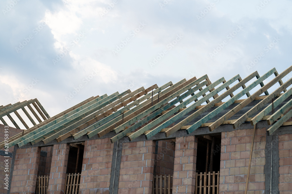 Residential construction site of terraced house or row homes. Roof truss wooden framework, structural components that provide support to the roof.