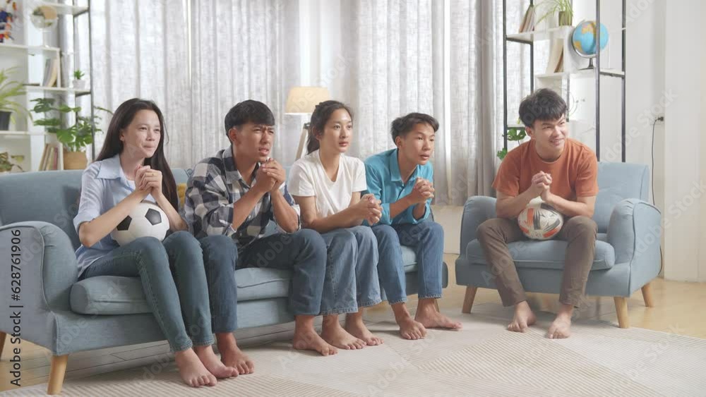 Asian Teenagers Cheering And Watching Football Game On Tv And Celebrating Victory At Home
