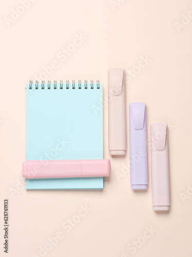 Notebook with a markers on a beige background. Top view
