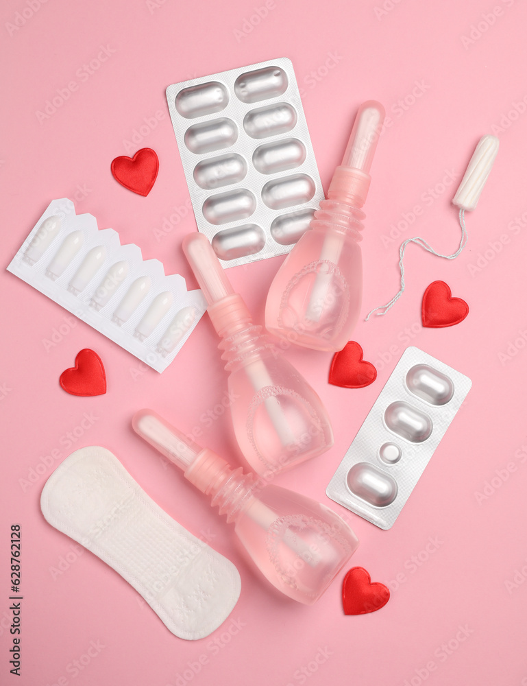 Obraz premium Women's health concept. Vaginal enemas, pad, tampon, pills and hearts on pink background. Flat lay