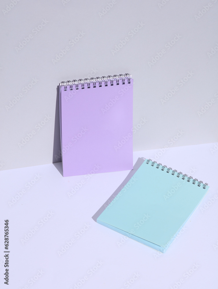 Purple and blue notebooks on a white background with a shadow. Creative layout, minimalism Purple and blue notebooks on a white background with a shadow. Creative layout, minimalism