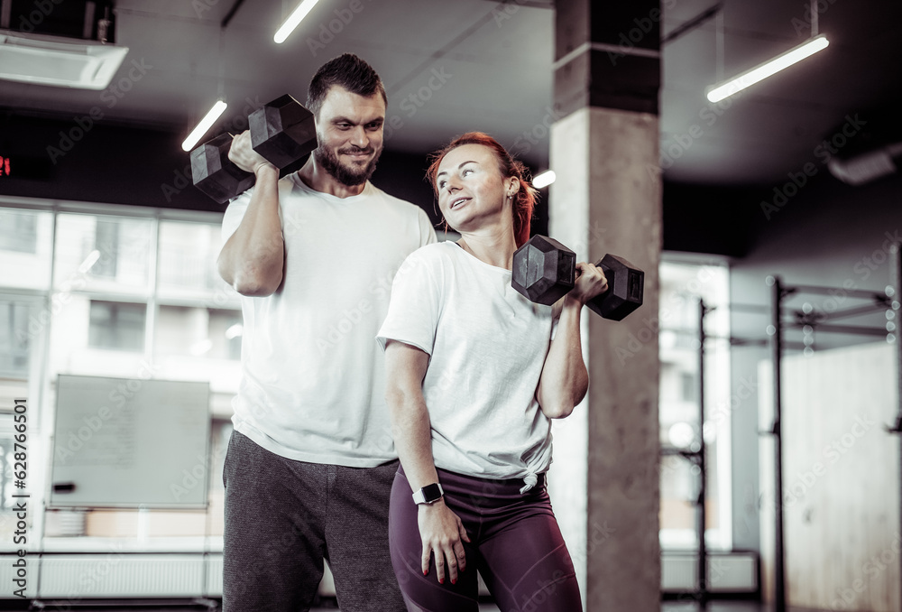 Smiling woman and man athlete with dumbbells in the gym. Healthy lifestyle