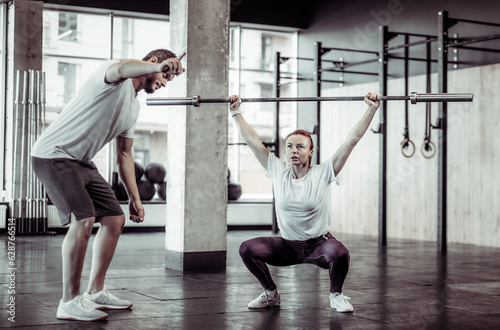 Young fitness woman training with personal trainer in modern gym
