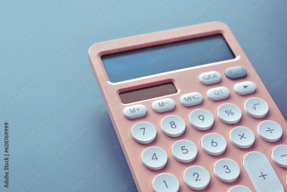 close up modern peach colour pastel calculator and white button on blue background, business and finance accounting concept close up modern peach colour pastel calculator and white button on blue background, business and finance accounting concept