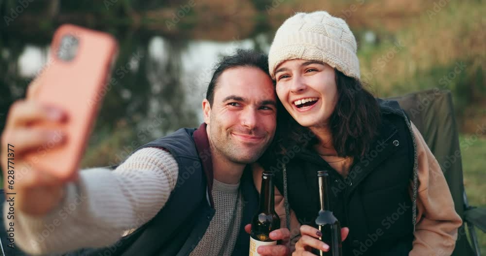 Selfie, camping and couple with beer by a river for a celebration and to update social media of a vacation together. Internet, travel and people happy for a online picture in the outdoor woods Selfie, camping and couple with beer by a river for a celebration and to update social media of a vacation together. Internet, travel and people happy for a online picture in the outdoor woods