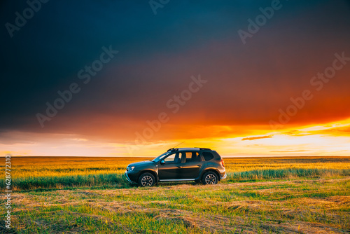 AWD 4WD SUV green car in summer meadow landscape in summer field countryside landscape. Sunset sky background. © Grigory Bruev
