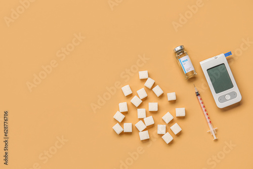 Glucometer with insulin, syringe and sugar on orange background. Diabetes concept