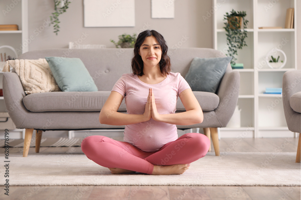 Sporty pregnant woman meditating at home