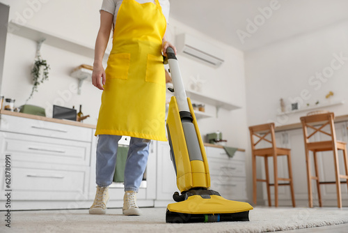 Woman in yellow apron vacuu...