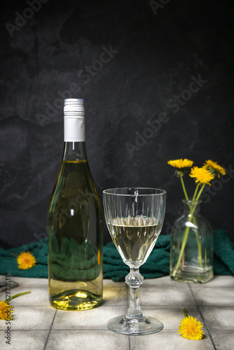 Bottle and glass of dandelion wine on grey tile table