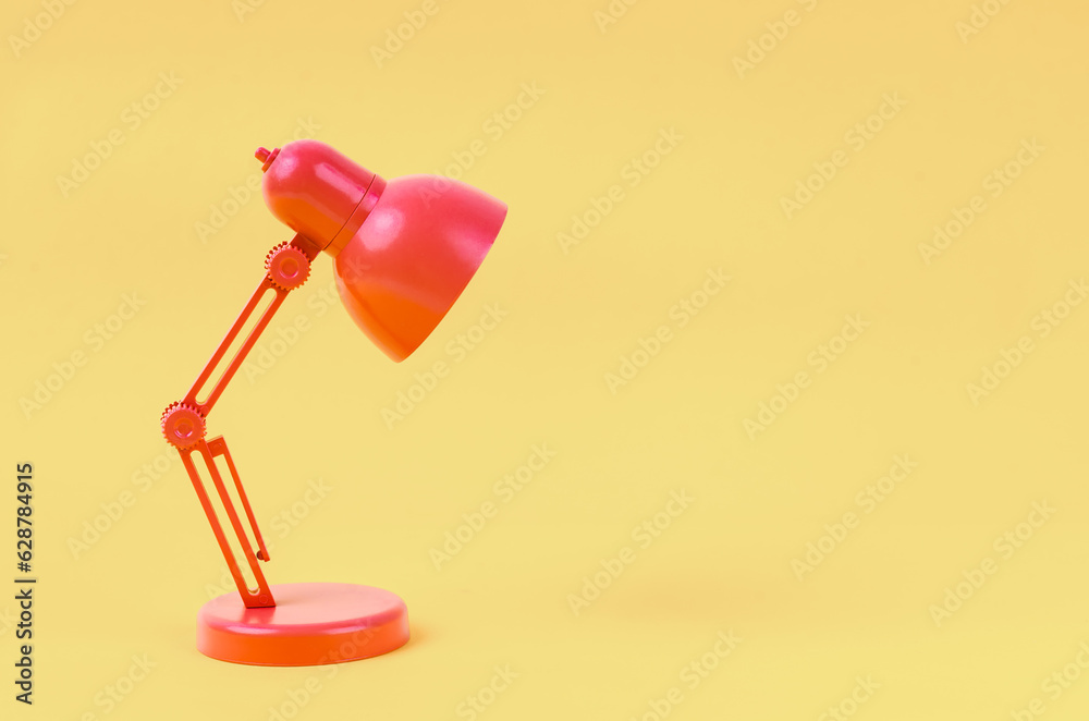 A Red folding table lamp on yellow background. A Red folding table lamp on yellow background.