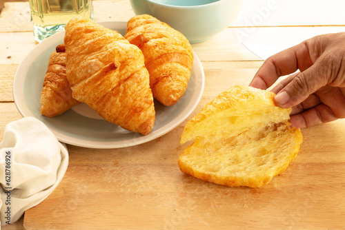 Croissant on wood table with cup of coffee and milk.
