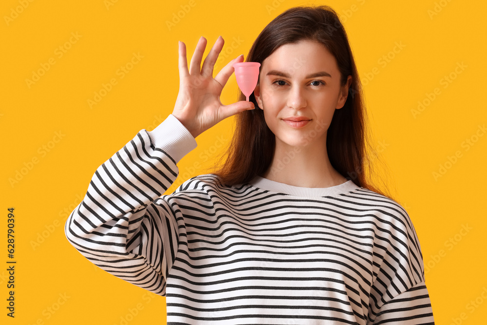 Young woman with menstrual cup on orange background Young woman with menstrual cup on orange background