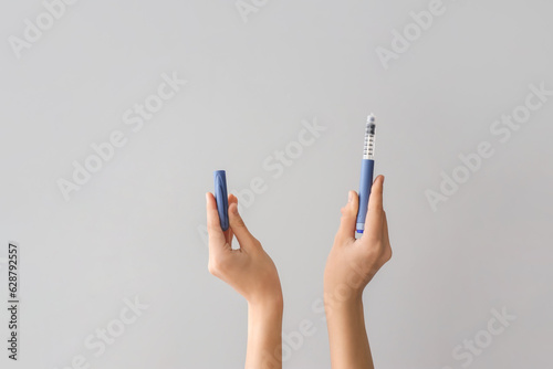 Female hands with insulin syringe on grey background