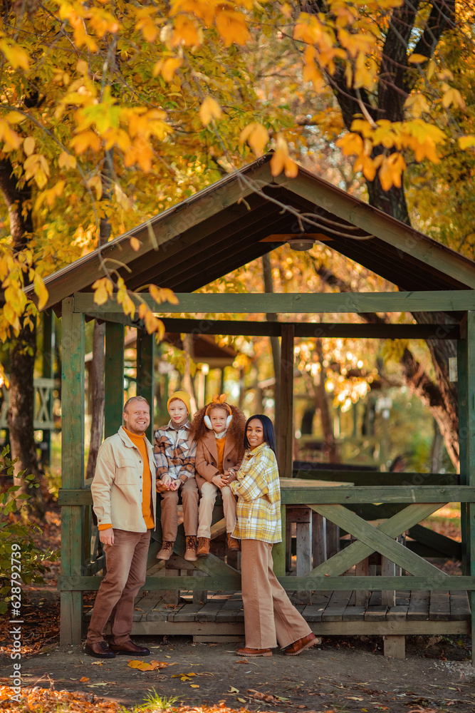 multiethnic family on a walk in the autumn park in a wooden gazebo
