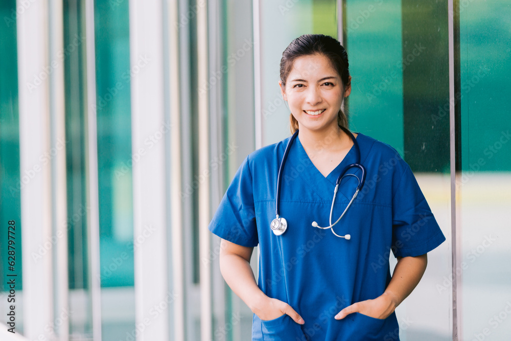 Portrait of young Asian female doctor standing outside hospital building with stethoscope.