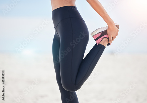 Fitness, woman and stretching leg at a beach for running, workout and body, exercise or wellness routine. Foot, stretch and female runner at the sea for training, sports and physical performance