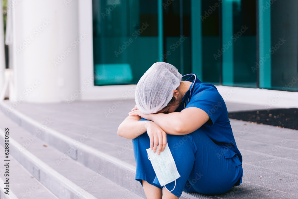 Upset nurse sitting on floor in hospital ward Upset nurse sitting on floor in hospital ward
