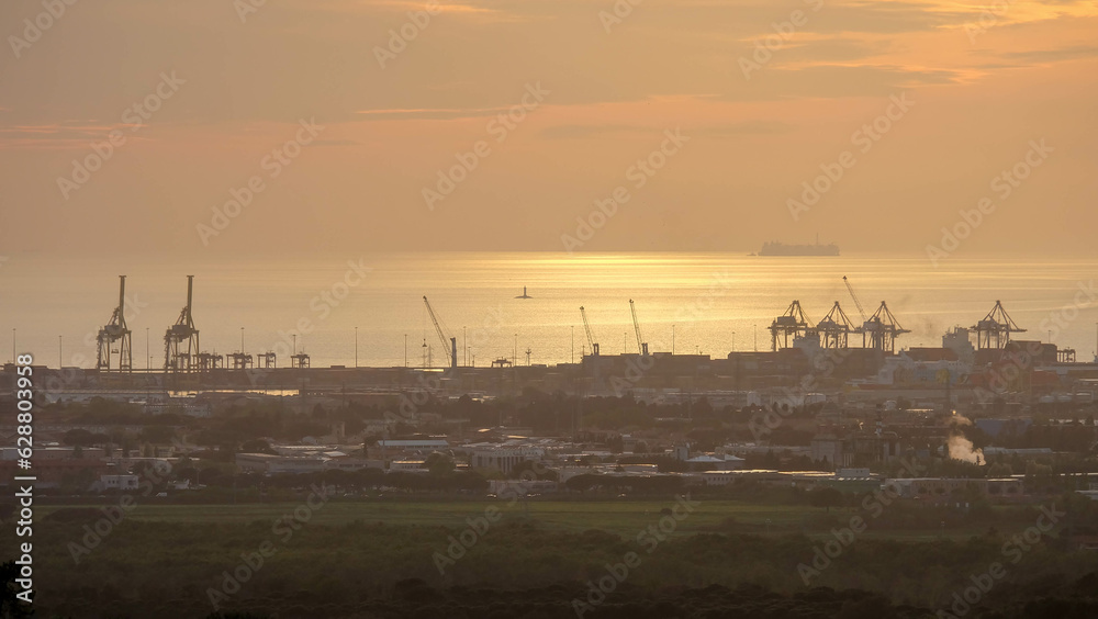 Strand von Livorno in Italien mit Industriehafen bei Sonnenuntergang Abendrot