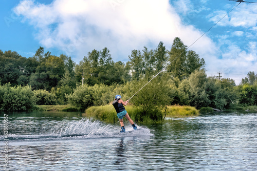 Wakeboarding on the sea on summer day in life jacket. Soft focus. Action blur.