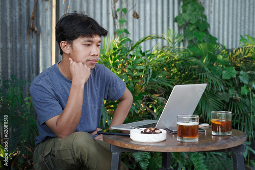 asian man using laptop in outdoor cafe photo