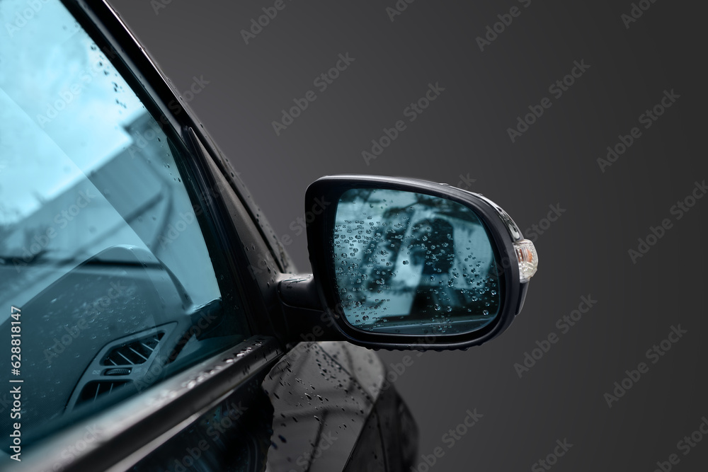 Black wing mirror of modern car. Car side rear-view mirror with water drops.