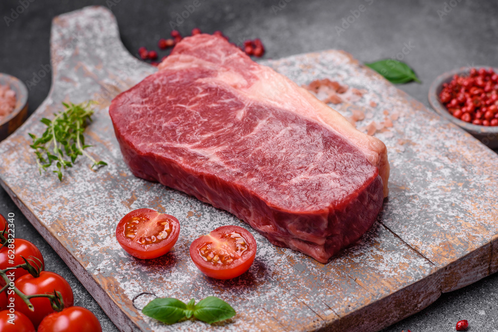 Fresh raw beef striploin steak with salt, spices and herbs