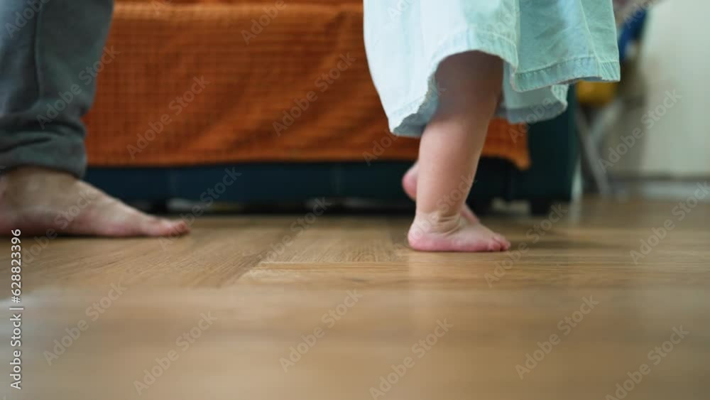 Baby first steps.Toddler at home takes funny first steps.Dad teaches child to walk, legs close-up.Toddler feet on laminate floor.Father's day child education.Kid dream study at home.walk baby learning Baby first steps.Toddler at home takes funny first steps.Dad teaches child to walk, legs close-up.Toddler feet on laminate floor.Father's day child education.Kid dream study at home.walk baby learning