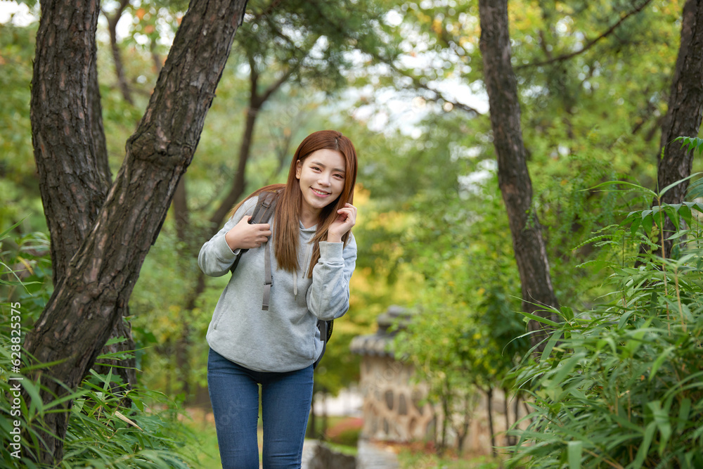 a young female college student traveling through the woods with a backpack a young female college student traveling through the woods with a backpack
