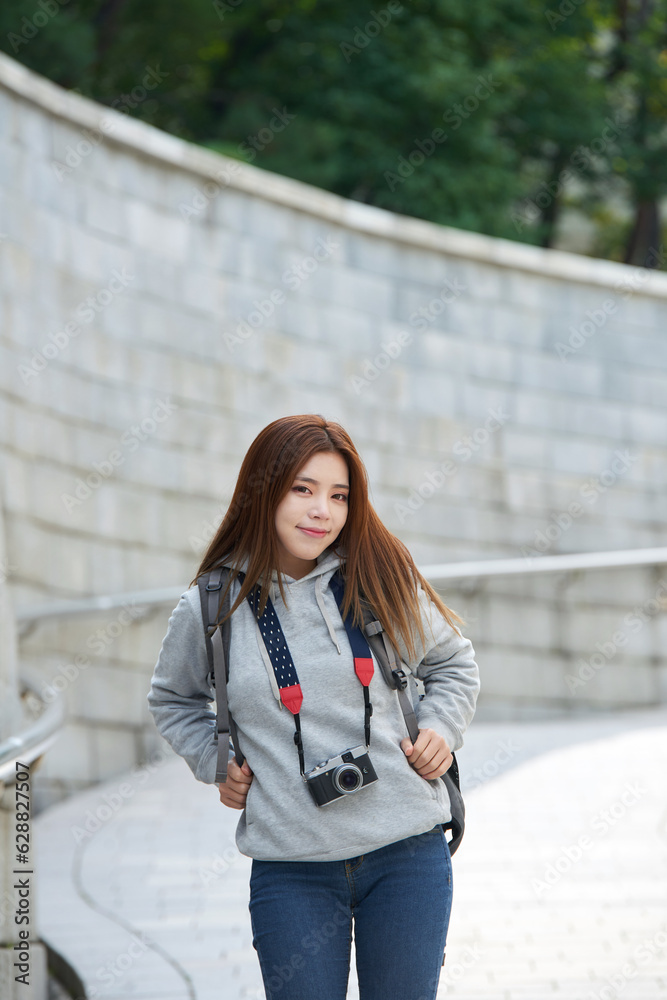 Fototapeta premium young woman who is taking pictures while traveling in Korea with a camera backpack