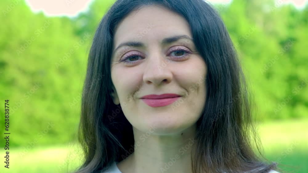 A 35-year-old brunette woman in nature turns her head to the camera and smiles A 35-year-old brunette woman in nature turns her head to the camera and smiles