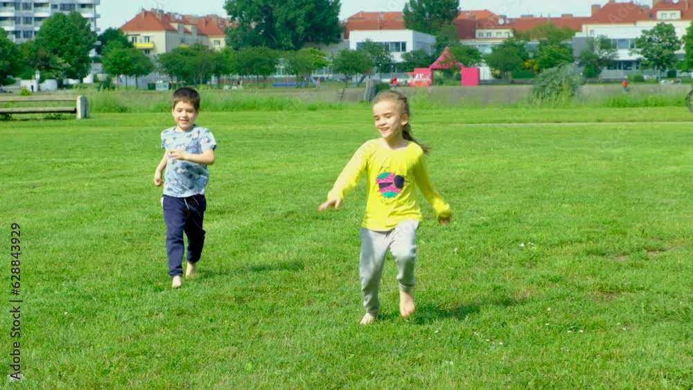 A little boy and a girl run barefoot on the grass. The concept of children's friendship and happy childhood A little boy and a girl run barefoot on the grass. The concept of children's friendship and happy childhood