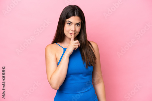 Young Brazilian woman isolated on pink background showing a sign of silence gesture putting finger in mouth