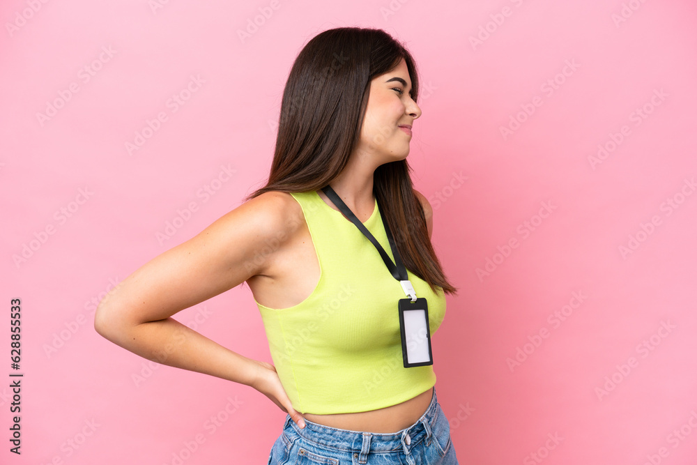 Young Brazilian woman with ID card isolated on pink background suffering from backache for having made an effort Young Brazilian woman with ID card isolated on pink background suffering from backache for having made an effort